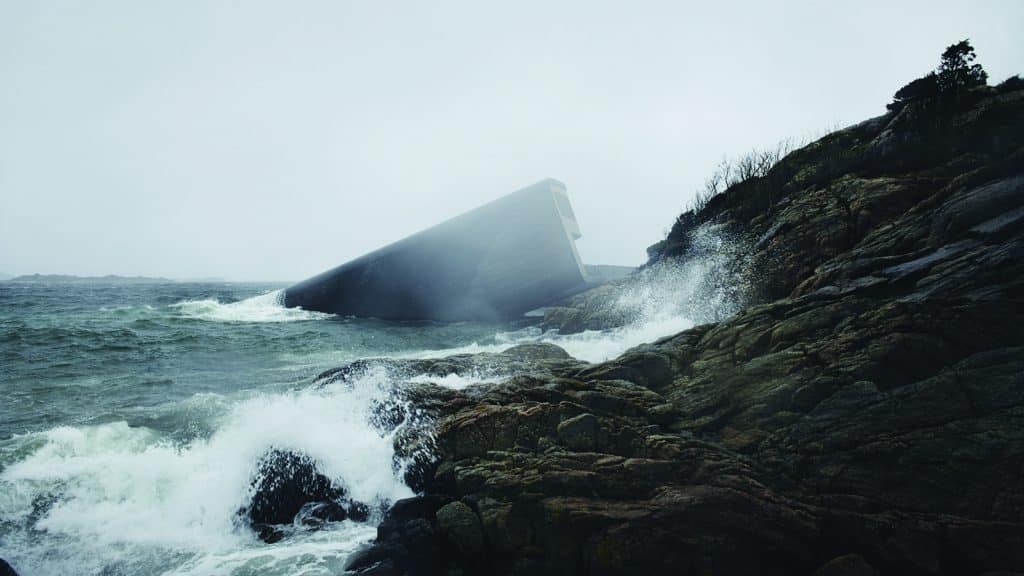 Moderne Architektur an einer stürmischen Küste – spektakuläre Installation im Meer mit Felsen und rauer See.