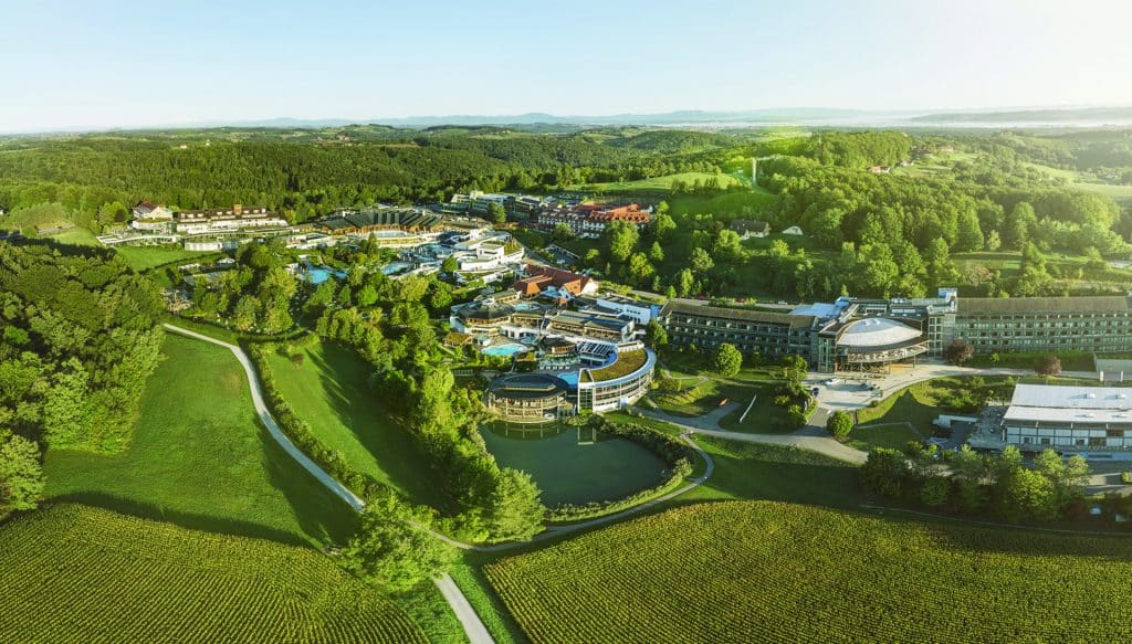 Luftaufnahme eines weitläufigen Thermenresorts in der Steiermark – umgeben von grüner Landschaft, Feldern und Hügeln.